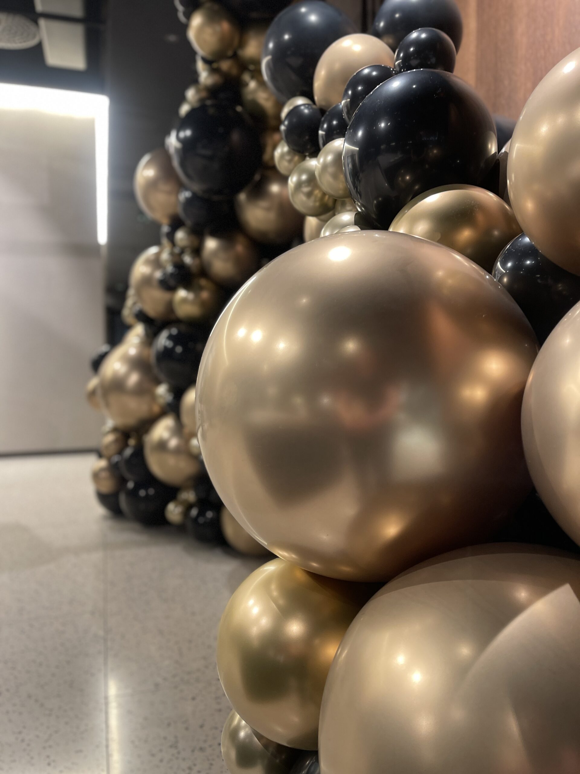 Nærbilde av organsike ballongsøyler i svarte og gull ballonger for Omega Holtan.